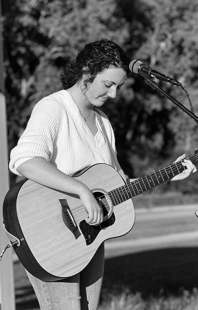 Gwendellyn Malee performing, head bowed over her guitar