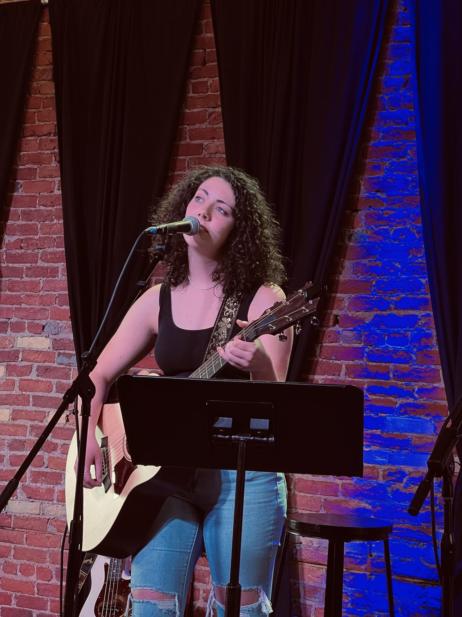 Gwendellyn performing solo with acoustic guitar at an intimate Nashville venue