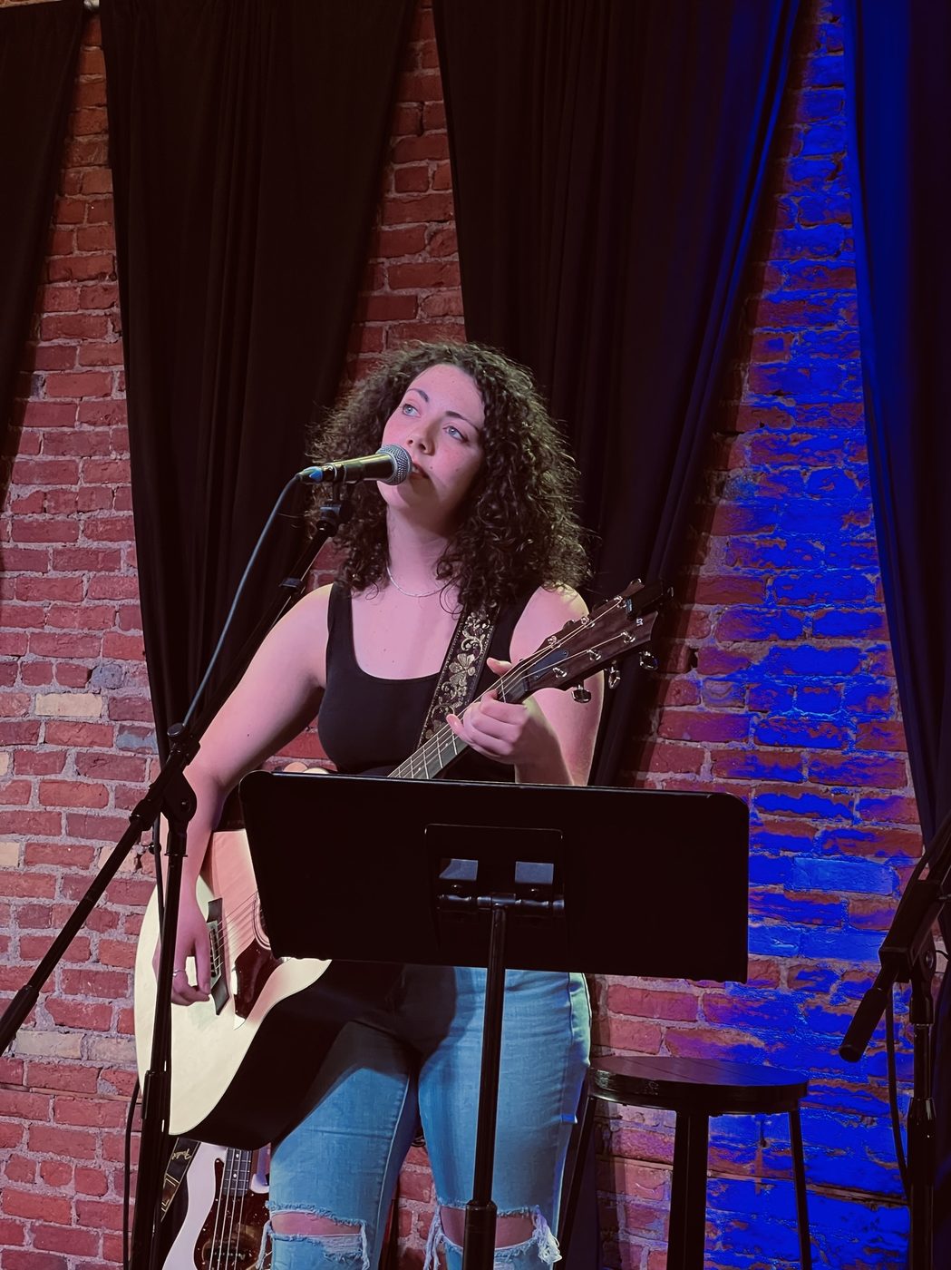 Gwendellyn performing on stage at a brick wall venue